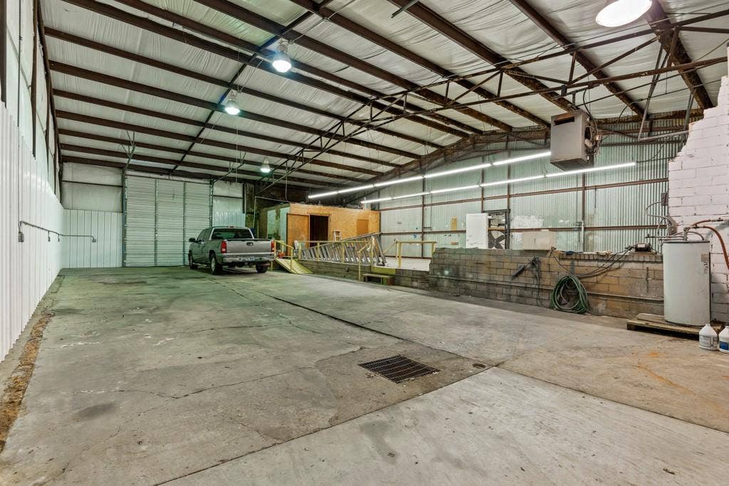 414 E Marshall Street, Gilmer, TX 75644 Spacious interior with concrete flooring and exposed metal beam ceiling