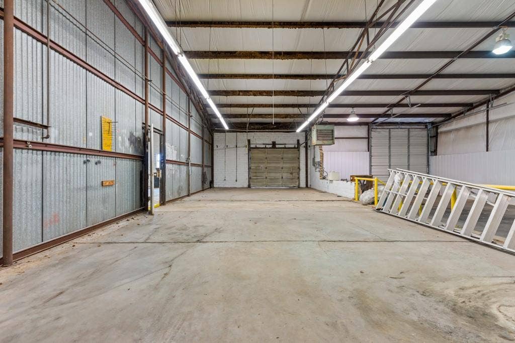 414 E Marshall Street, Gilmer, TX 75644 Expansive concrete flooring with corrugated metal wall paneling and exposed structural beams