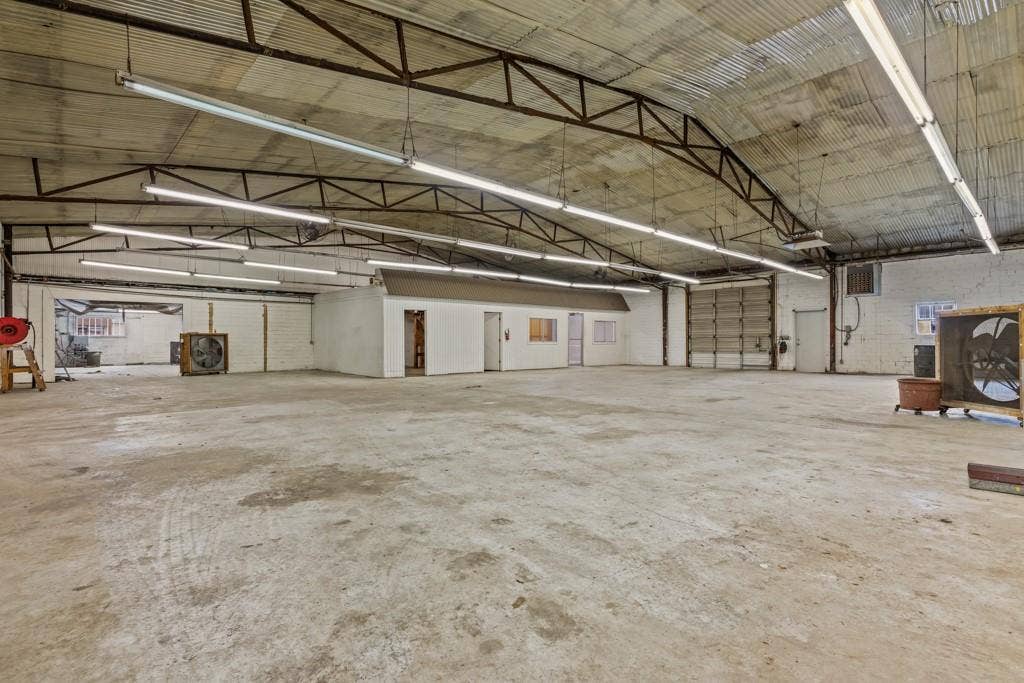 414 E Marshall Street, Gilmer, TX 75644 Expansive concrete flooring with a corrugated metal ceiling and exposed metal trusses