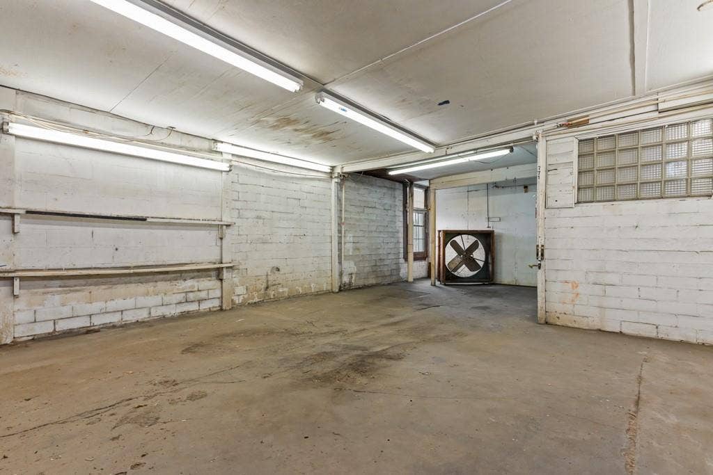 414 E Marshall Street, Gilmer, TX 75644 Concrete flooring with painted brick walls, exposed fluorescent lighting, and a large industrial fan