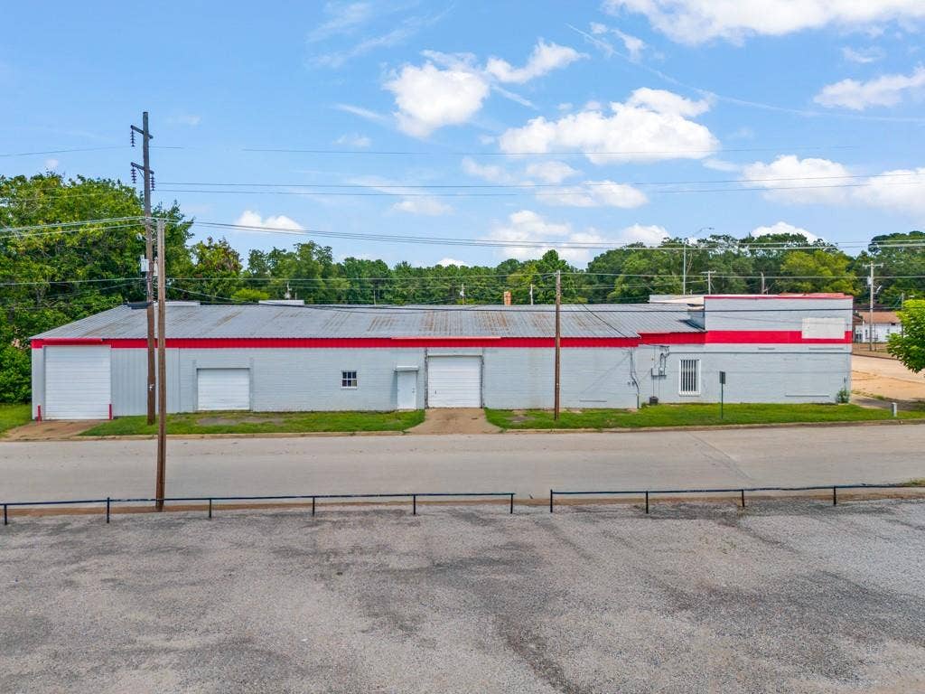 414 E Marshall Street, Gilmer, TX 75644 Light gray commercial building with a corrugated metal roof and red trim