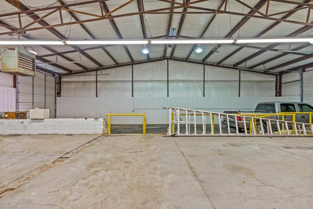 414 E Marshall Street, Gilmer, TX 75644 Large open warehouse space featuring concrete flooring and exposed metal beam ceiling