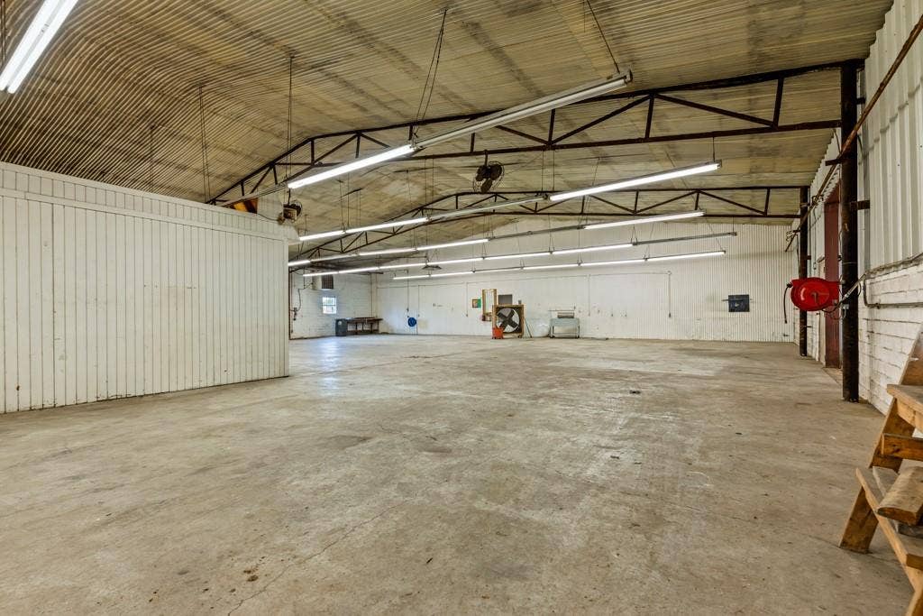 414 E Marshall Street, Gilmer, TX 75644 Concrete flooring, corrugated metal ceiling, exposed structural beams, fluorescent lighting fixtures, and painted panel walls
