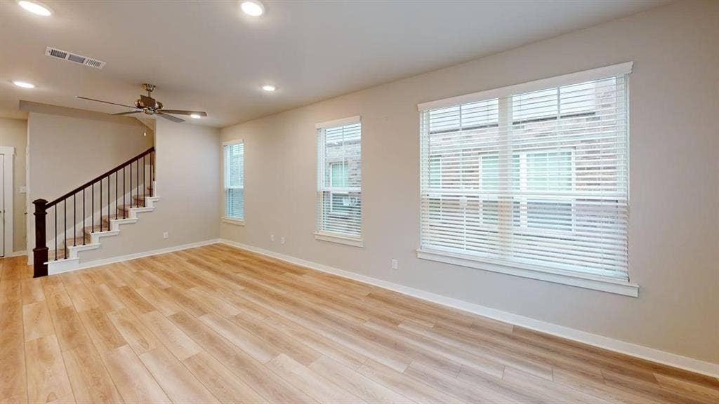 Wood-finish flooring throughout, multiple windows with blinds, recessed lighting, and a ceiling fan