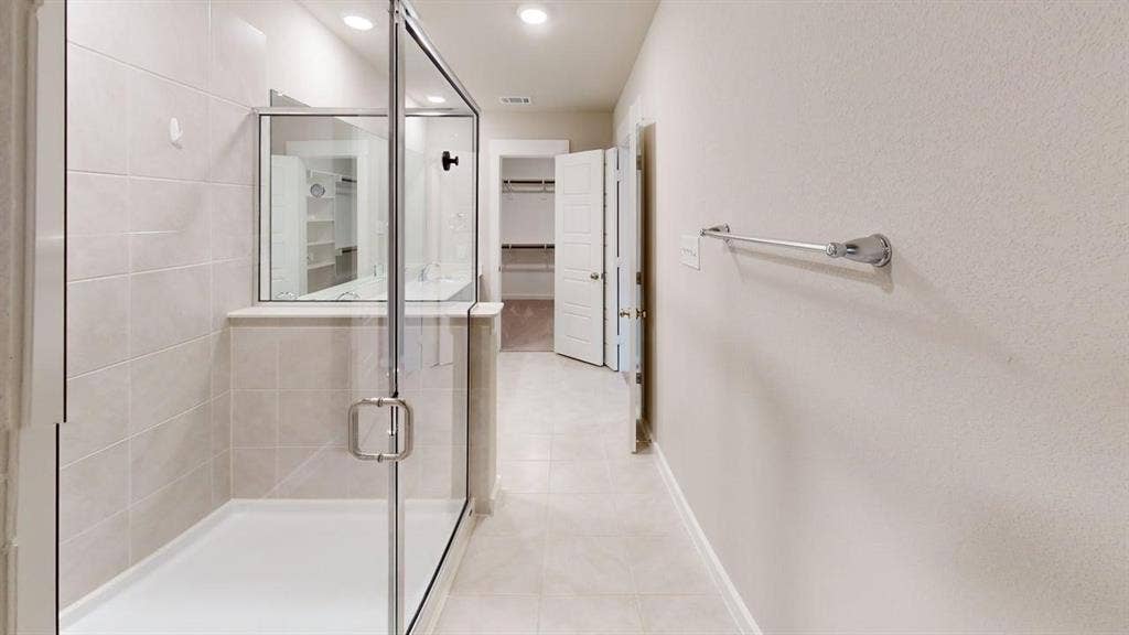 Glass-enclosed shower with a tiled surround, recessed lighting, and tile flooring