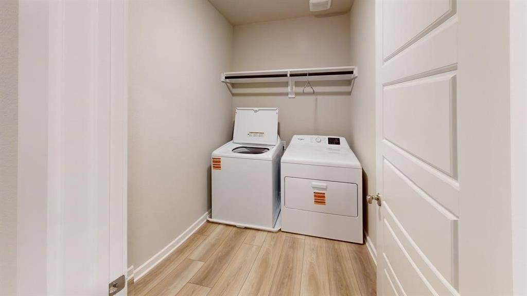 Dedicated laundry area featuring wood-finish flooring and a built-in shelf