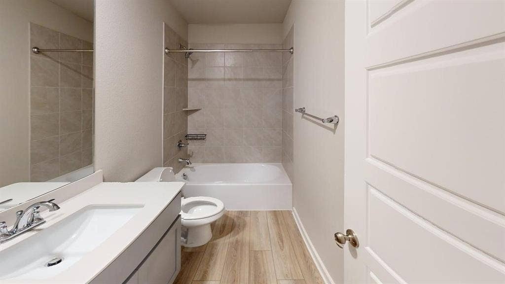 Wood-finish flooring with a white vanity featuring a rectangular undermount sink and chrome faucet