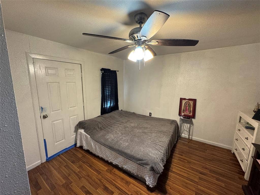 407 S Garrett Avenue, Dallas, TX 75223 Bedroom with a textured wall, dark wood finished floors, a ceiling fan, and a textured ceiling