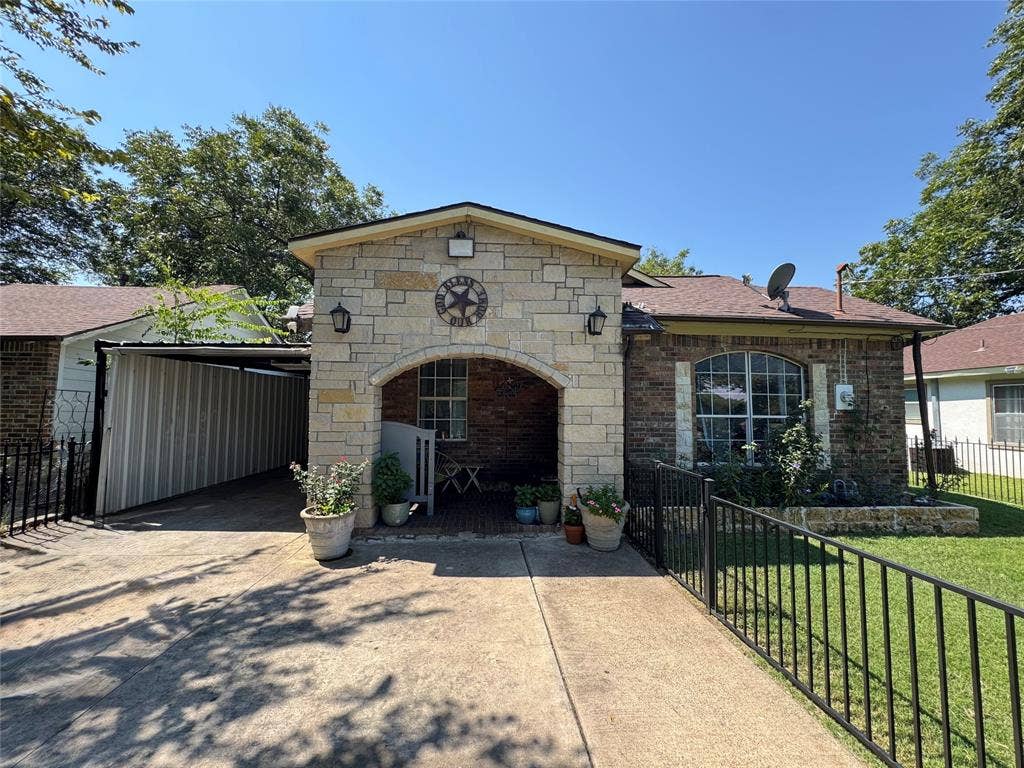 407 S Garrett Avenue, Dallas, TX 75223 View of front of home with stone siding, concrete driveway, brick siding, and a carport