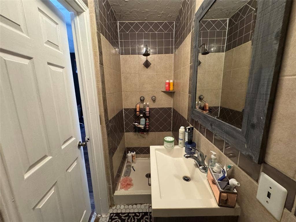 407 S Garrett Avenue, Dallas, TX 75223 Full bathroom featuring vanity, tile walls, and tiled shower