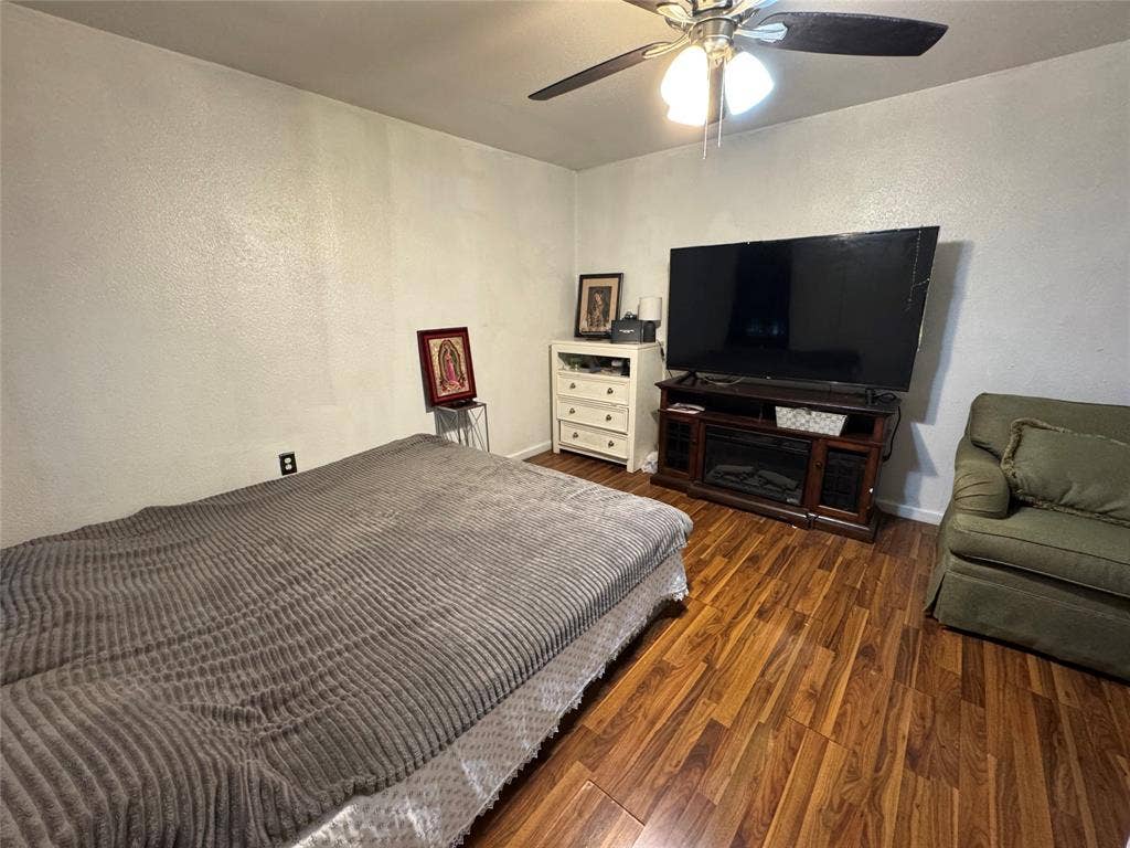 407 S Garrett Avenue, Dallas, TX 75223 Bedroom featuring dark wood finished floors, a ceiling fan, and a textured wall
