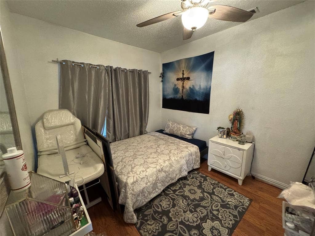 407 S Garrett Avenue, Dallas, TX 75223 Bedroom with dark wood finished floors, a textured ceiling, ceiling fan, and a textured wall