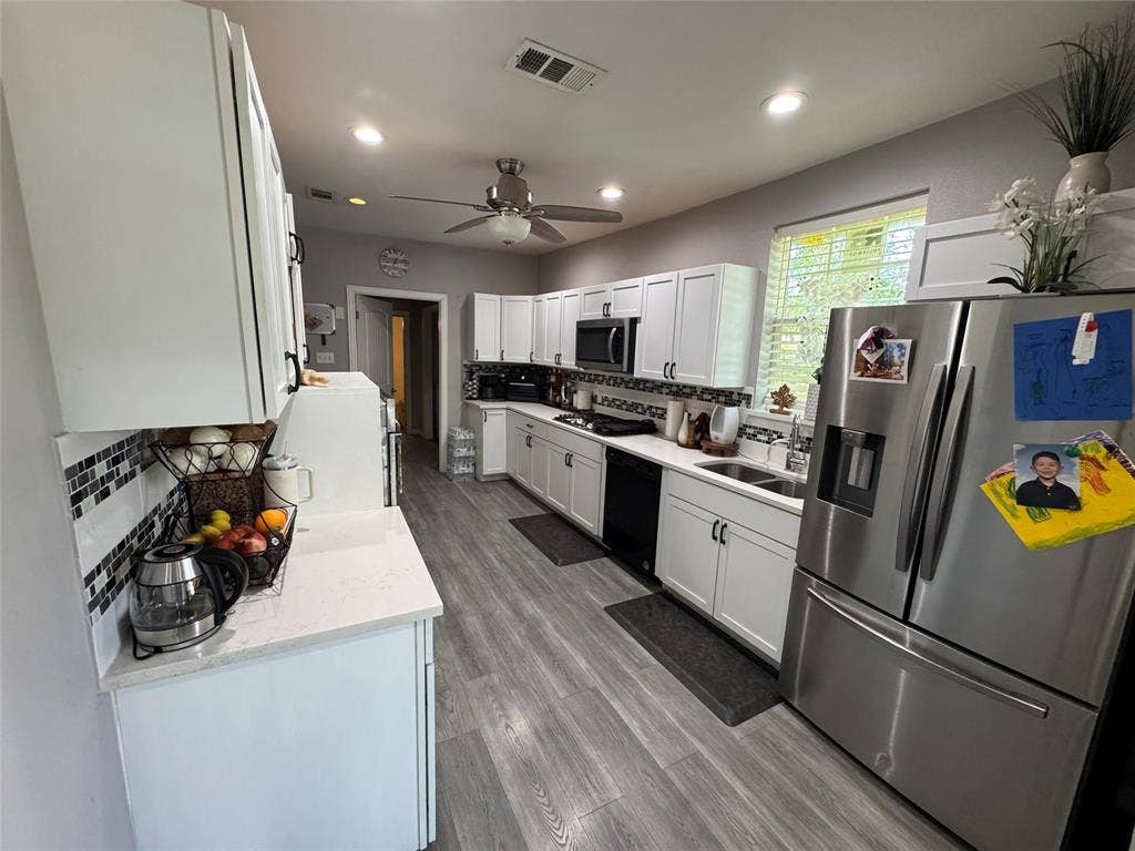 407 S Garrett Avenue, Dallas, TX 75223 Kitchen with stainless steel appliances, tasteful backsplash, light stone countertops, white cabinets, and recessed lighting