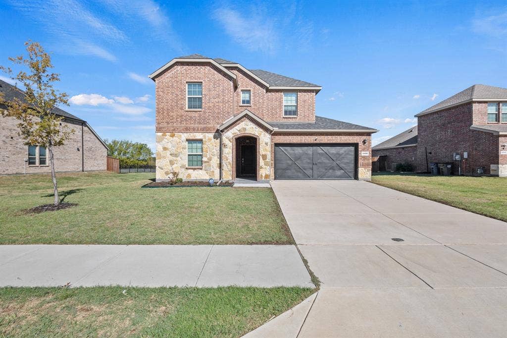 1536 Estivella Drive, Little Elm, TX 75068 Brick and stone facade, arched entry, two-story construction, attached garage with decorative door, concrete driveway