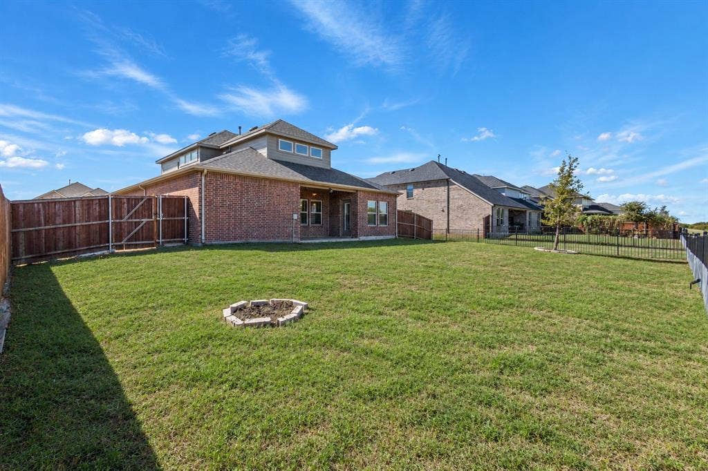 1536 Estivella Drive, Little Elm, TX 75068 Expansive backyard featuring a manicured lawn, full privacy fencing, and a built-in fire pit