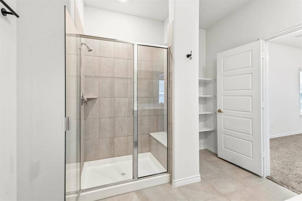 1536 Estivella Drive, Little Elm, TX 75068 Walk-in shower with clear glass enclosure, integrated bench, and tiled walls