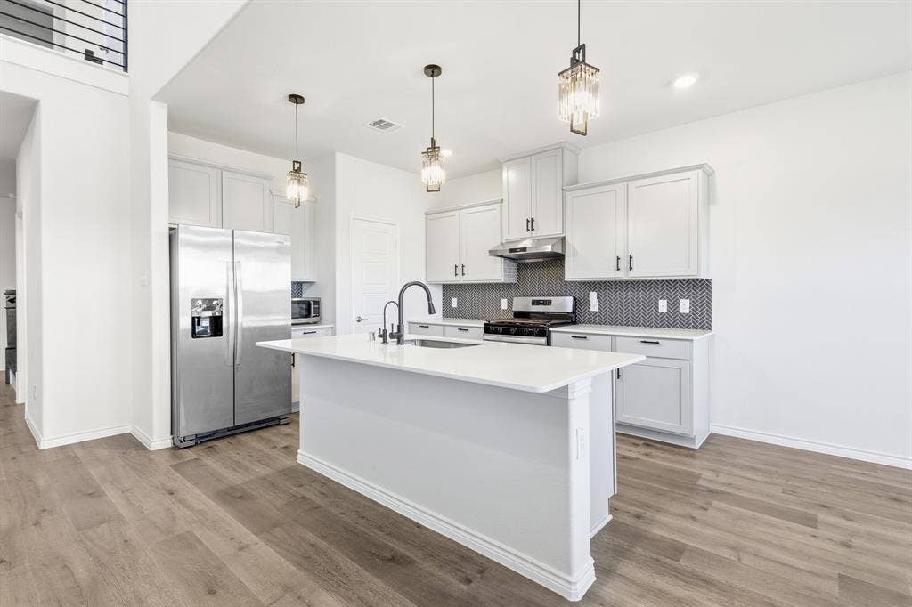 1536 Estivella Drive, Little Elm, TX 75068 White kitchen cabinetry with black hardware, stainless steel appliances, and a mosaic tile backsplash