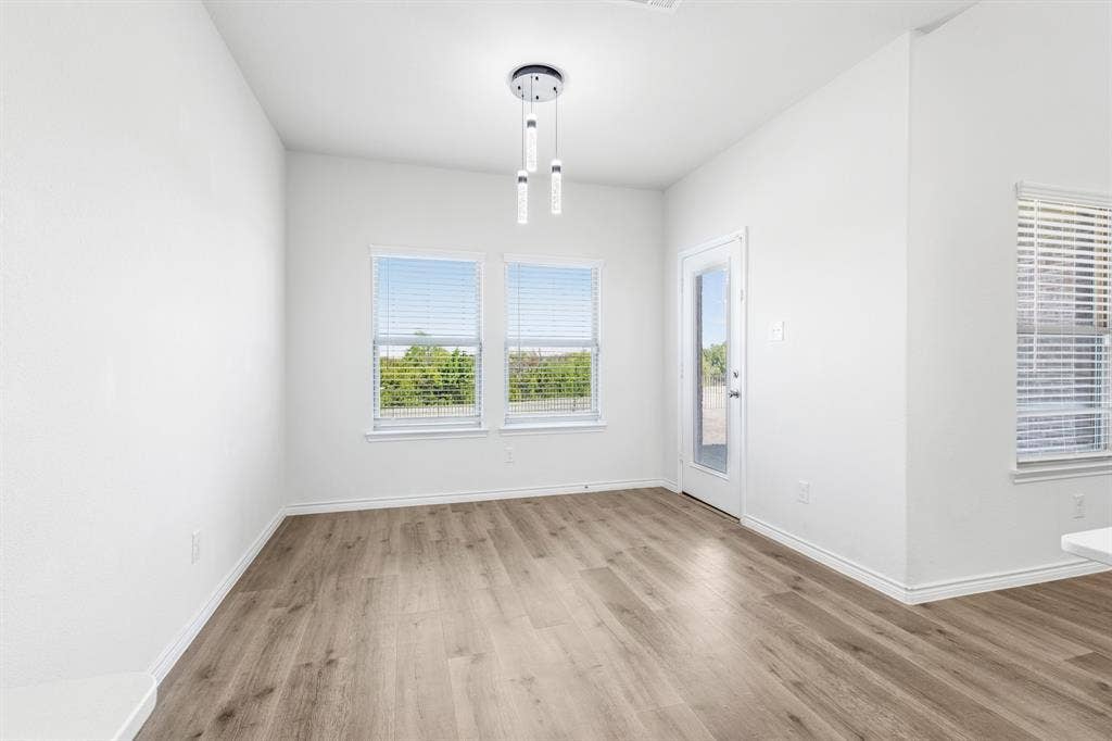 1536 Estivella Drive, Little Elm, TX 75068 Wood-finish flooring, white walls, and a contemporary chandelier