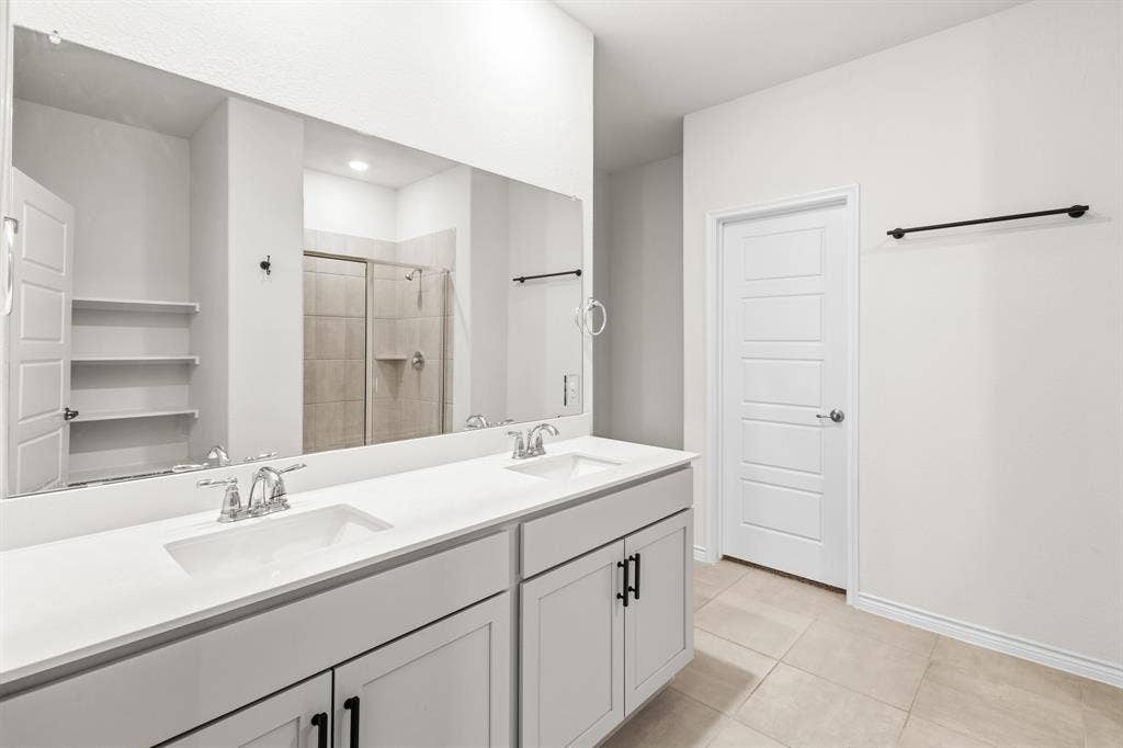 1536 Estivella Drive, Little Elm, TX 75068 Dual vanity with integrated sinks, expansive wall mirror, and light-toned tile flooring