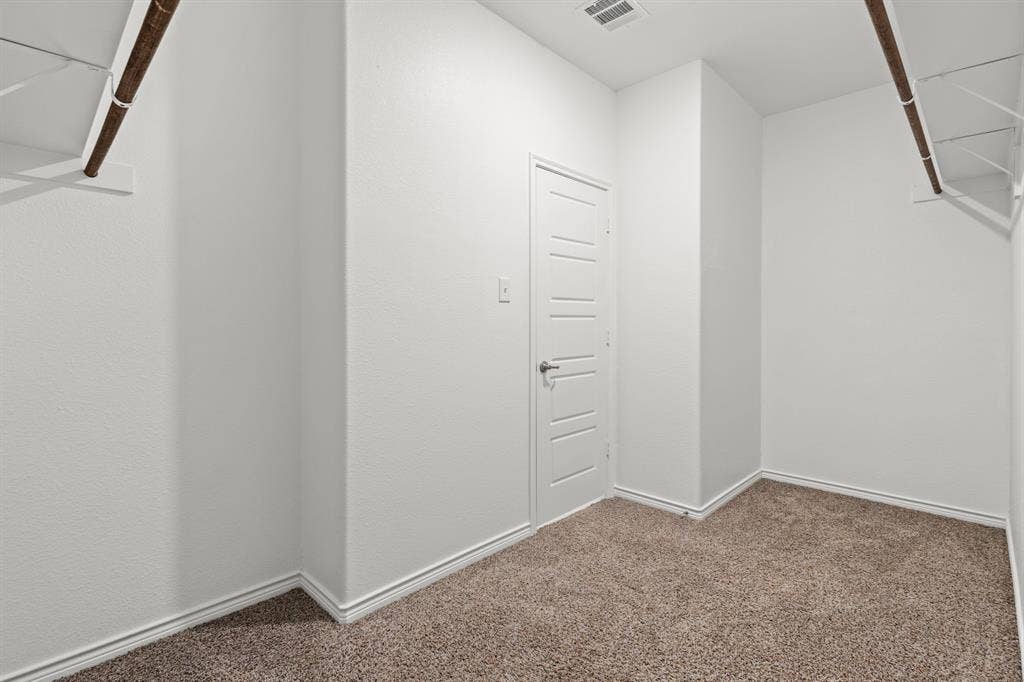 1536 Estivella Drive, Little Elm, TX 75068 Plush carpet flooring, white walls, storage shelving, and a paneled door with a lever handle