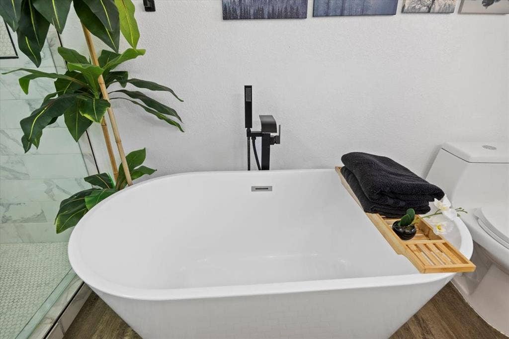 5920 Tourist Drive, North Richland Hills, TX 76117 White freestanding tub with a matte black floor-mounted faucet.
