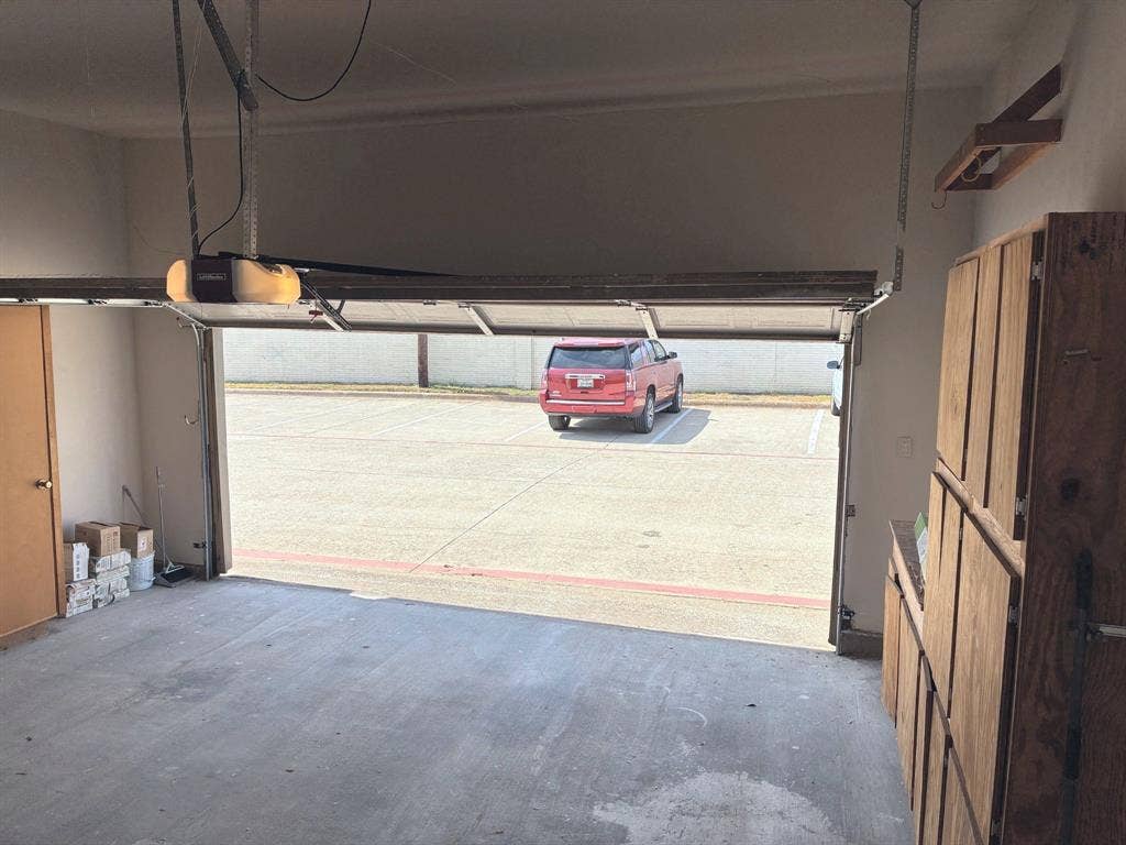 Garage featuring a concrete floor, motorized overhead door, and built-in wood-finish cabinetry