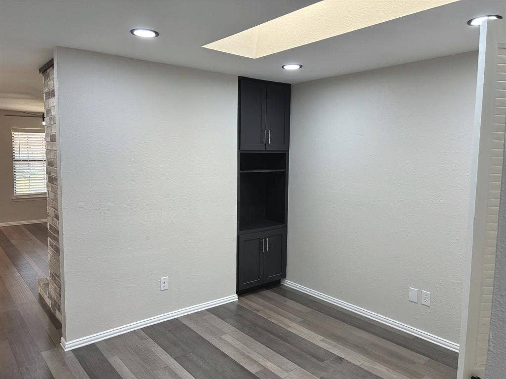 Built-in dark cabinetry with open shelving, wood-finish flooring, recessed lighting, and a recessed ceiling feature