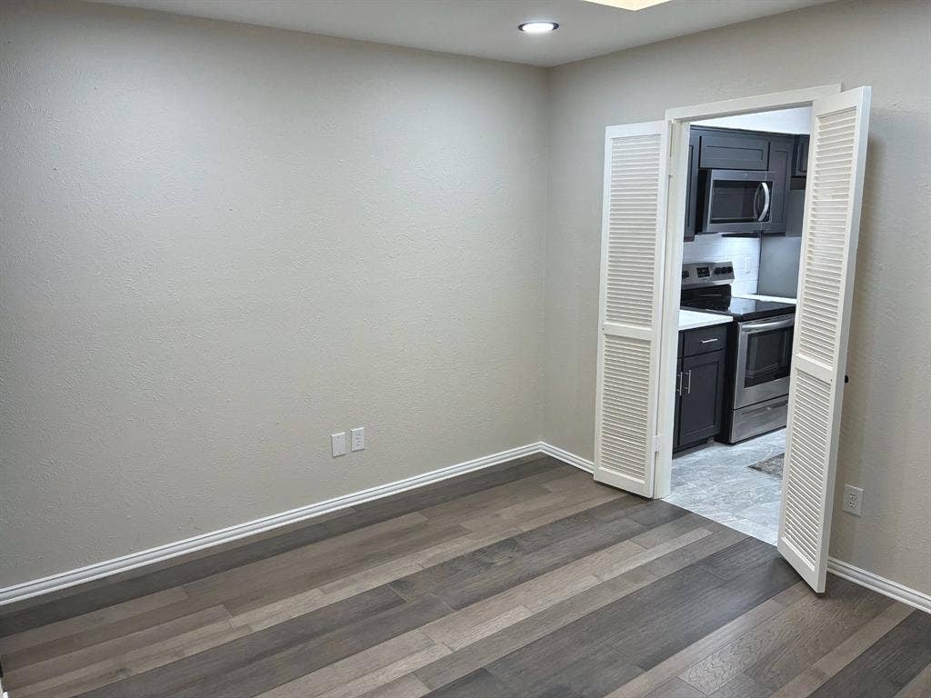 Room featuring wood-finish flooring, recessed lighting, and white louvered double doors