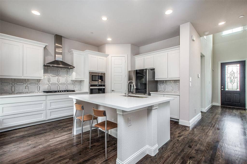 4944 Mckinney Hollow Drive, McKinney, TX 75070 Kitchen featuring white cabinetry, stainless steel appliances, a center island with seating, and wood-finish flooring