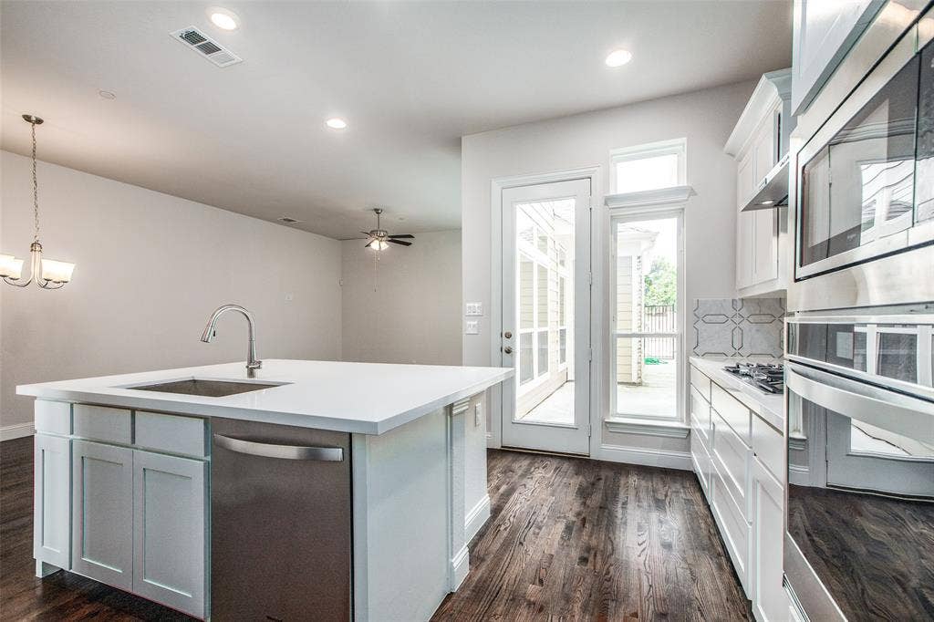 4944 Mckinney Hollow Drive, McKinney, TX 75070 Kitchen featuring a center island with sink, stainless steel appliances, white cabinetry, and wood-finish flooring