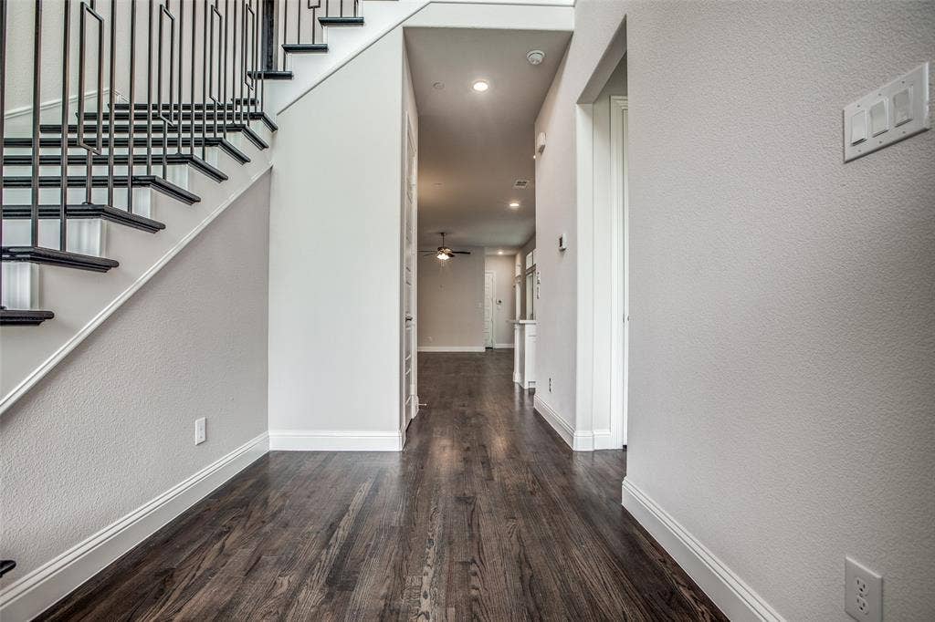 4944 Mckinney Hollow Drive, McKinney, TX 75070 Dark wood-finish flooring with white baseboards, a staircase featuring black metal balusters and dark treads, recessed lighting, and a white interior door