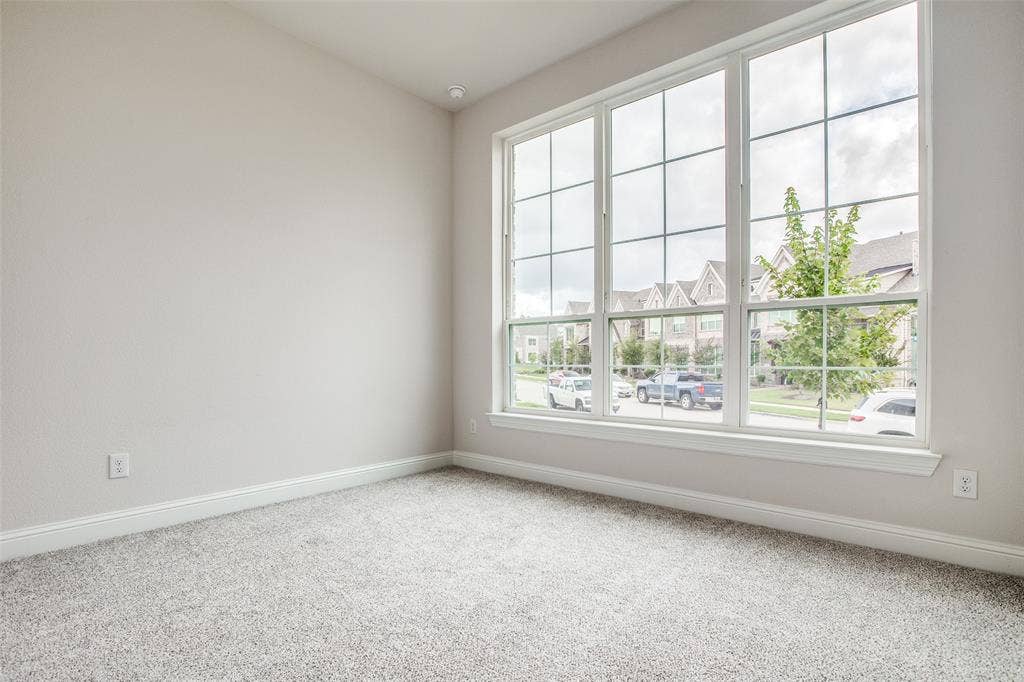 4944 Mckinney Hollow Drive, McKinney, TX 75070 Expansive window wall with grid pattern, neutral gray wall finish, recessed lighting, and light-toned carpet