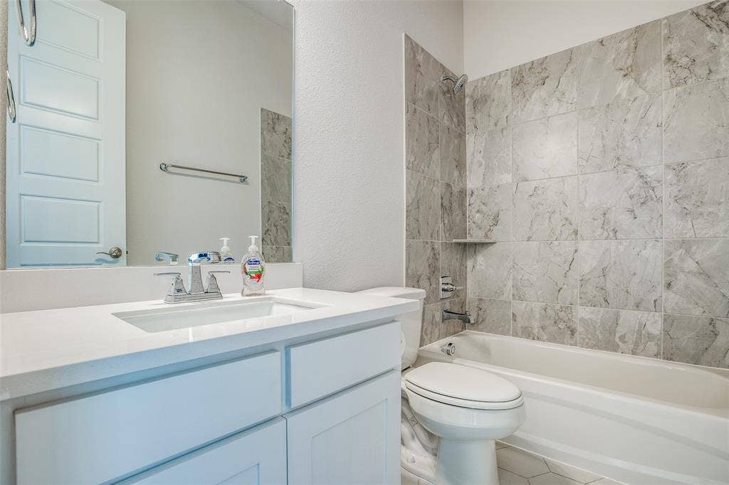 4944 Mckinney Hollow Drive, McKinney, TX 75070 White vanity with an integrated sink and chrome faucet, white countertop, and framed mirror