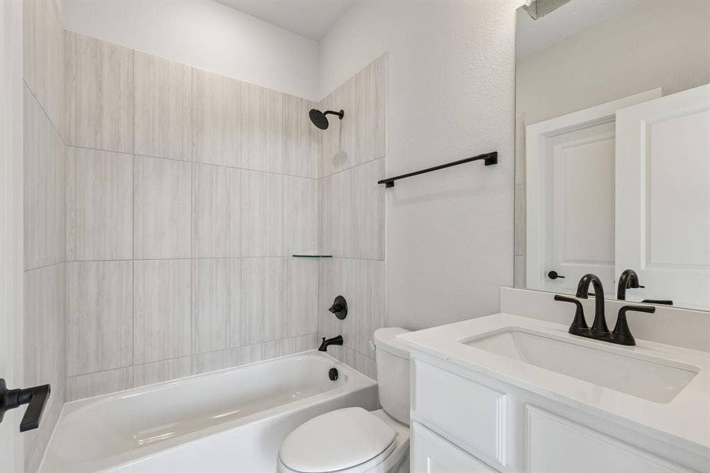 410 Rancher Trail, Waxahachie, TX 75165 Shower-tub combination with tile surround, glass shelf, and matte black fixtures