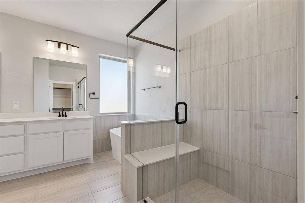 410 Rancher Trail, Waxahachie, TX 75165 Spacious bathroom featuring a glass-enclosed shower with a built-in bench, a separate soaking tub, and a vanity with dual sinks