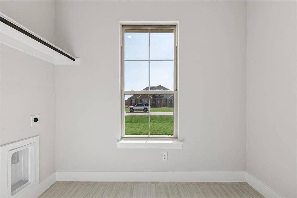 410 Rancher Trail, Waxahachie, TX 75165 Single-hung window, light wood-finish flooring, white wall paint, wall-mounted drying rack, and built-in washing machine utility box