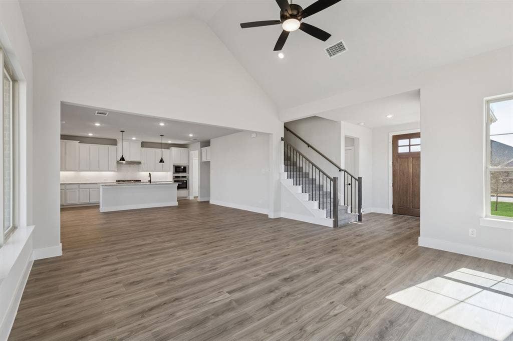 410 Rancher Trail, Waxahachie, TX 75165 Vaulted ceiling, wood-finish flooring, staircase with metal balusters, kitchen with pendant lighting and built-in appliances, and a paneled entry door