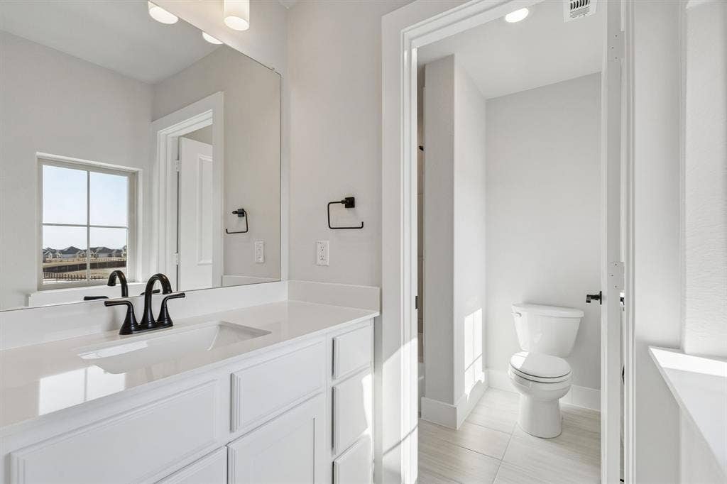 410 Rancher Trail, Waxahachie, TX 75165 White vanity with integrated sink, black faucet, and a large wall-mounted mirror