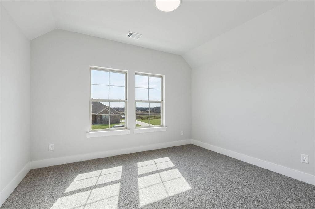 410 Rancher Trail, Waxahachie, TX 75165 Vaulted ceiling, two windows with gridded panes, light gray carpet flooring, white trim, and a flush mount ceiling light