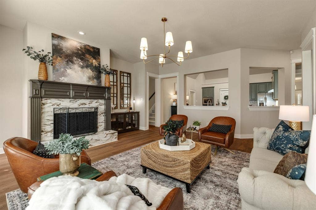 630 Candlewood Trail, Murphy, TX 75094 Wood-finish flooring, a fireplace with a decorative mantel and stone surround, and an overhead multi-arm chandelier
