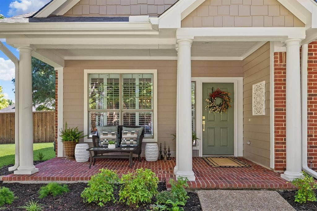 630 Candlewood Trail, Murphy, TX 75094 Covered front porch with brick flooring, decorative columns, and a paneled entry door
