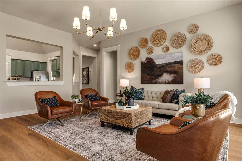 630 Candlewood Trail, Murphy, TX 75094 Spacious living area featuring wood-finish flooring, a contemporary chandelier, and a pass-through opening to the kitchen with green cabinetry