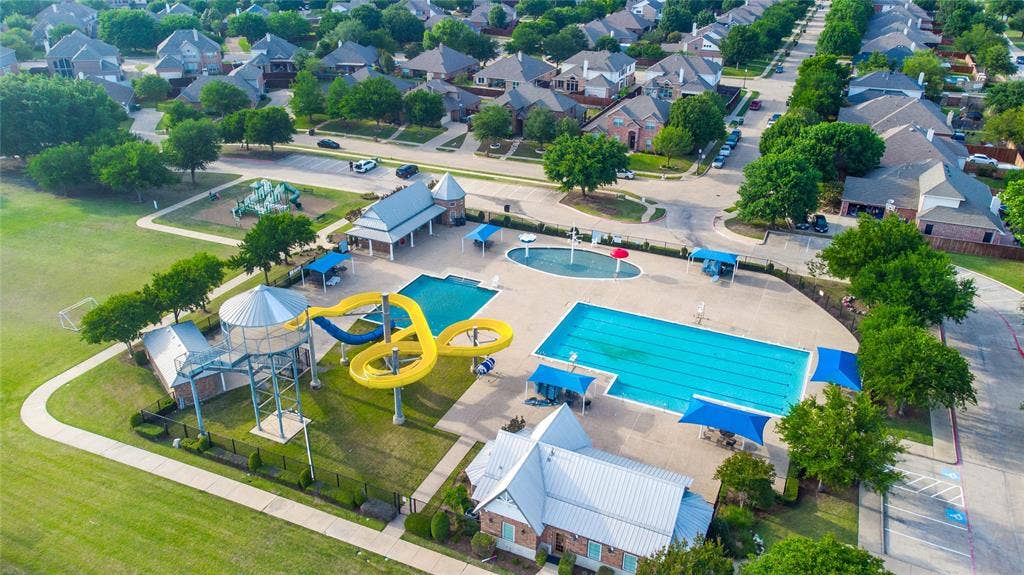 630 Candlewood Trail, Murphy, TX 75094 Community swimming pool with water slides, a recreational splash pad, lap lanes, and shade structures, surrounded by green spaces and residential streets