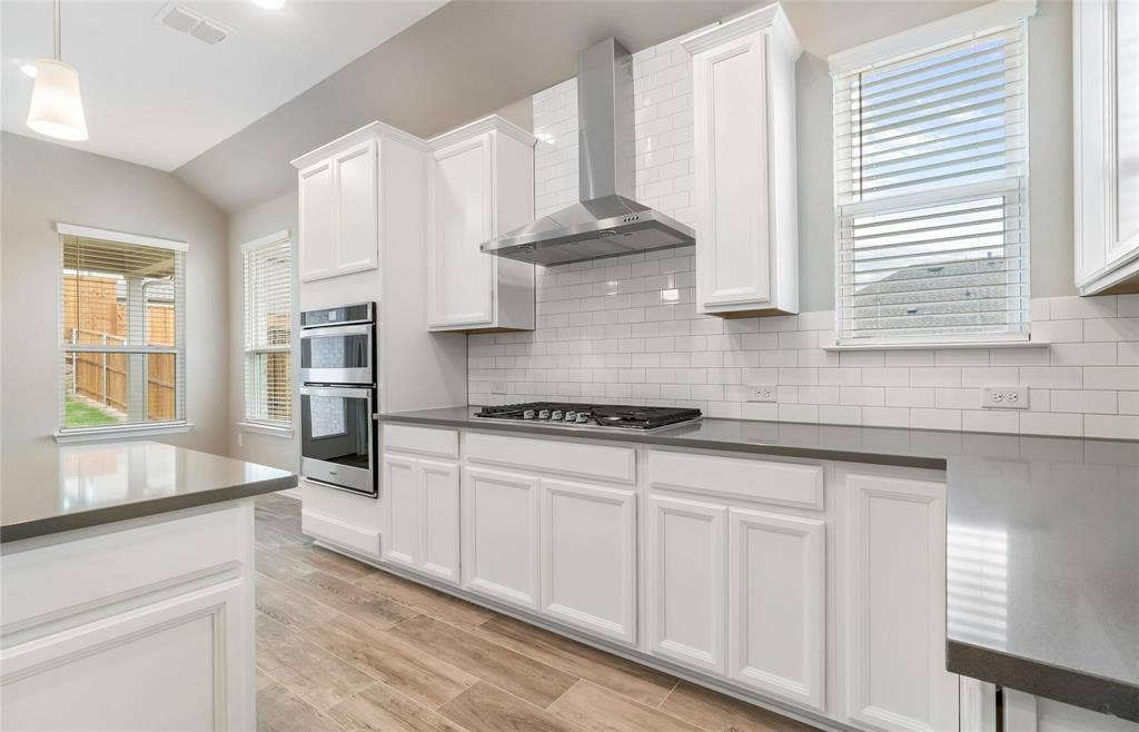 2816 southampton Drive, McKinney, TX 75071 Kitchen featuring shaker-style white cabinetry, dark countertops, a subway tile backsplash, stainless steel double ovens, and wood-finish flooring