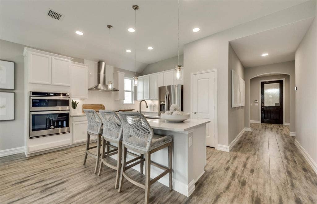 2816 southampton Drive, McKinney, TX 75071 Kitchen featuring white cabinetry, stainless steel appliances, wood-finish flooring, and an island with pendant lighting