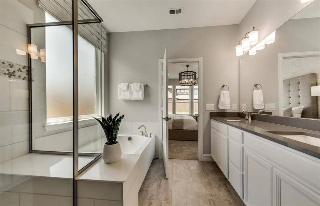 2816 southampton Drive, McKinney, TX 75071 Dual vanity with undermount sinks, a built-in soaking tub, a separate glass-enclosed shower, a frosted window, and wood-finish flooring