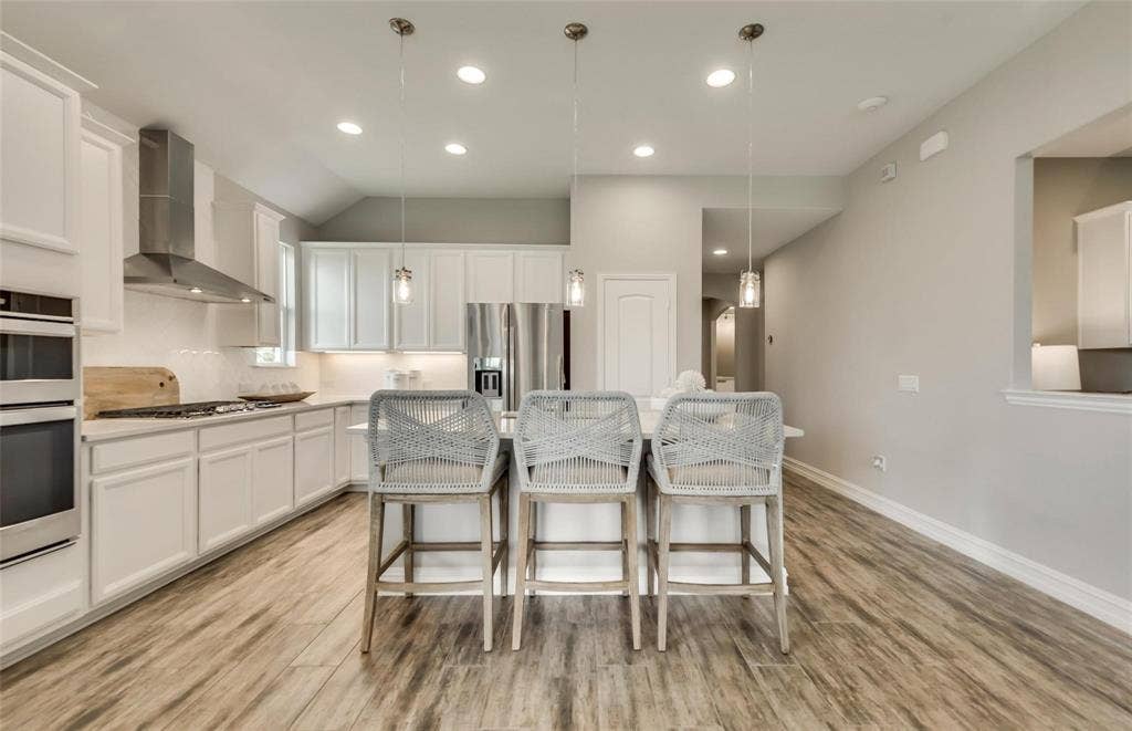2816 southampton Drive, McKinney, TX 75071 White cabinetry, stainless steel appliances, wood-finish flooring, recessed lighting, and a kitchen island with pendant lighting