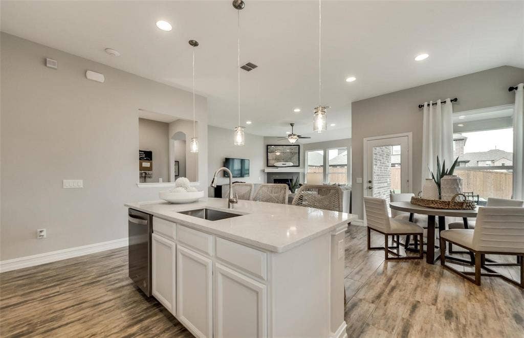 2816 southampton Drive, McKinney, TX 75071 Open-concept living space with wood-finish flooring, recessed lighting, and a kitchen island featuring a stainless steel sink and appliance