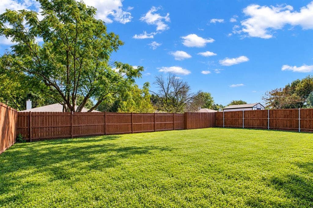 Expansive lawn area with a full privacy fence and mature trees
