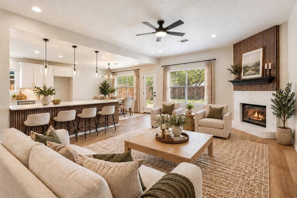 Open-concept living space featuring wood-finish flooring, a white-painted fireplace with a dark wood mantel, and an accent wall with vertical wood paneling